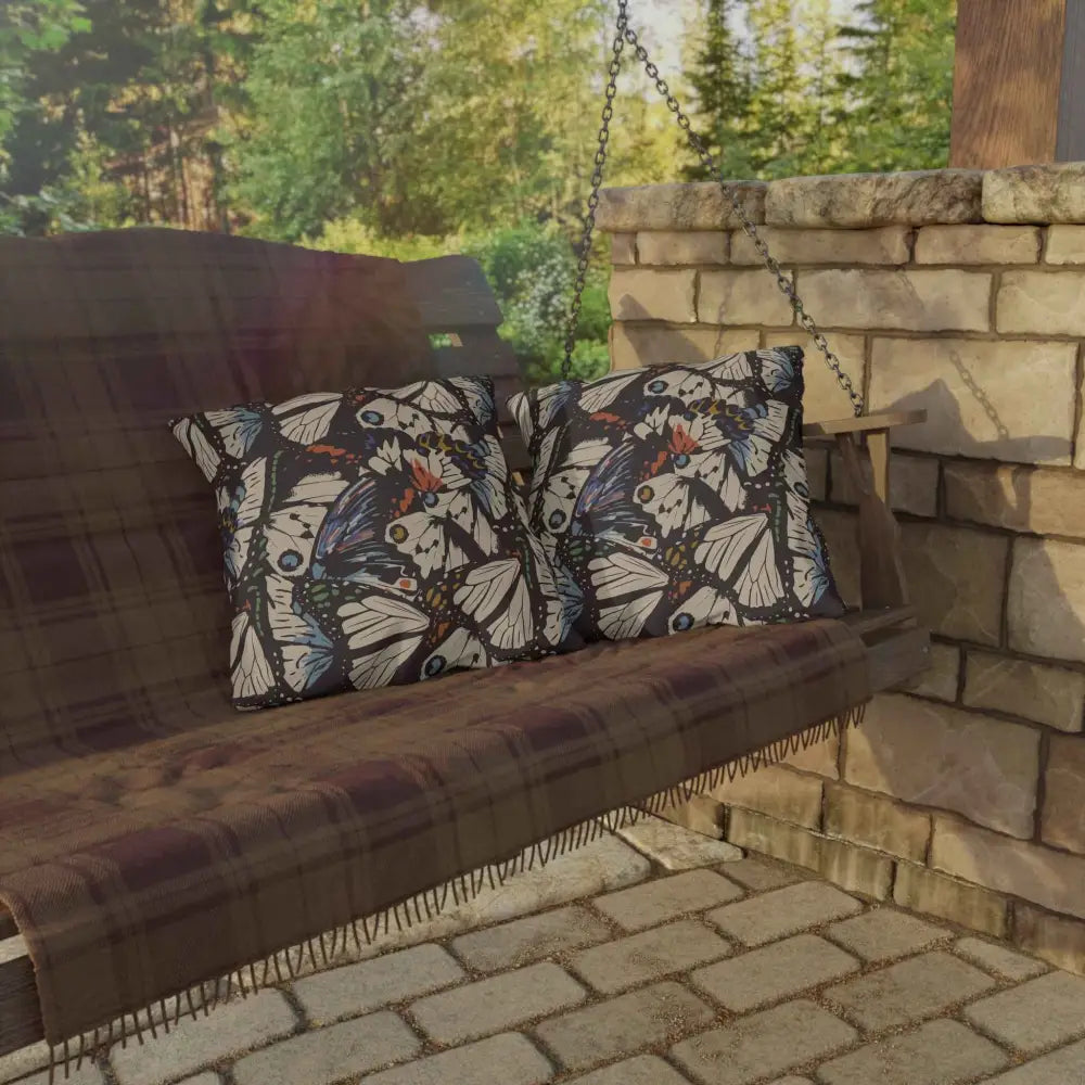 Wooden outdoor lounge swing with butterfly pillows and plaid blanket for outdoor lounge space