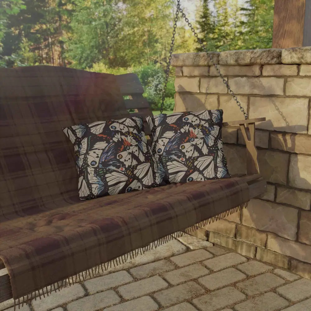 Wooden outdoor lounge swing with butterfly pillows and plaid blanket for outdoor lounge space