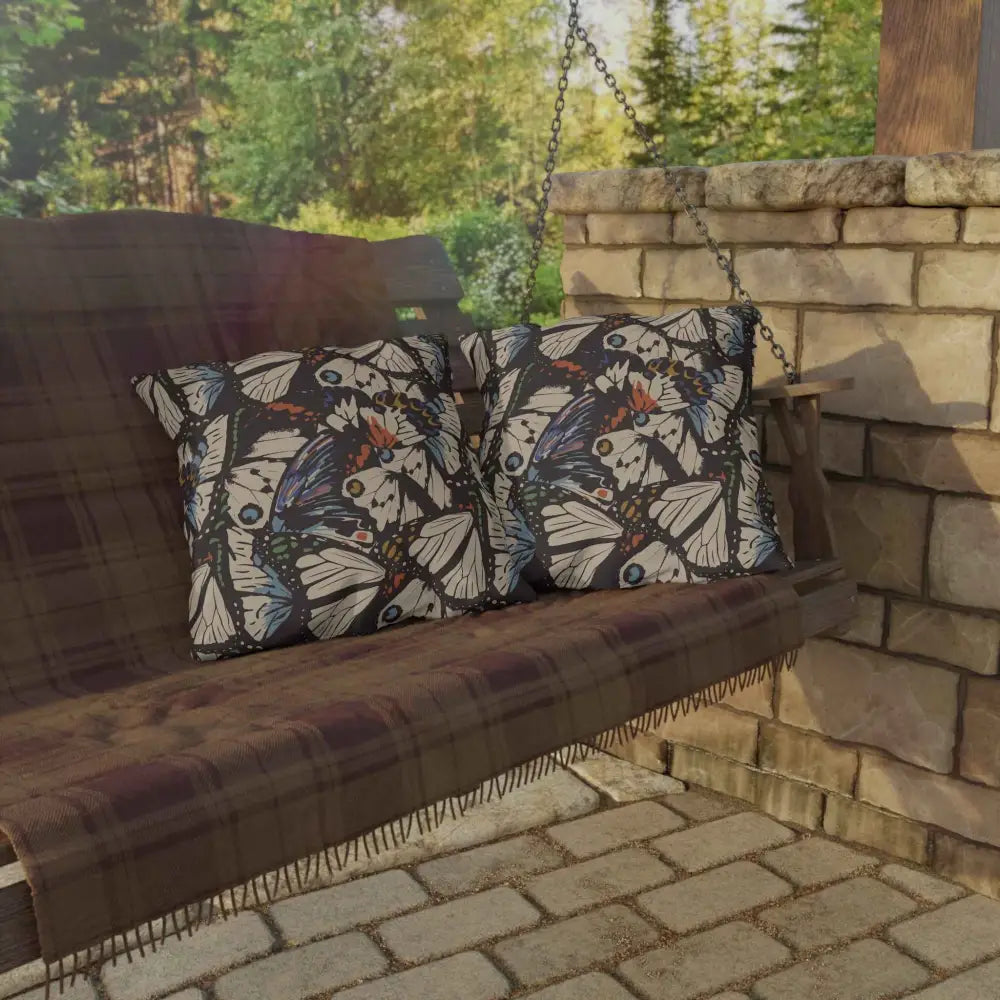 Outdoor lounge space with butterfly-patterned pillows and plaid blanket on wooden porch swing
