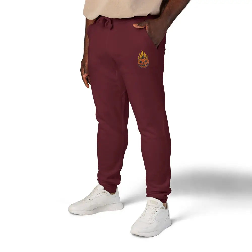 Maroon fleece sweatpants with flaming pumpkin emblem on left thigh for cozy Halloween streetwear