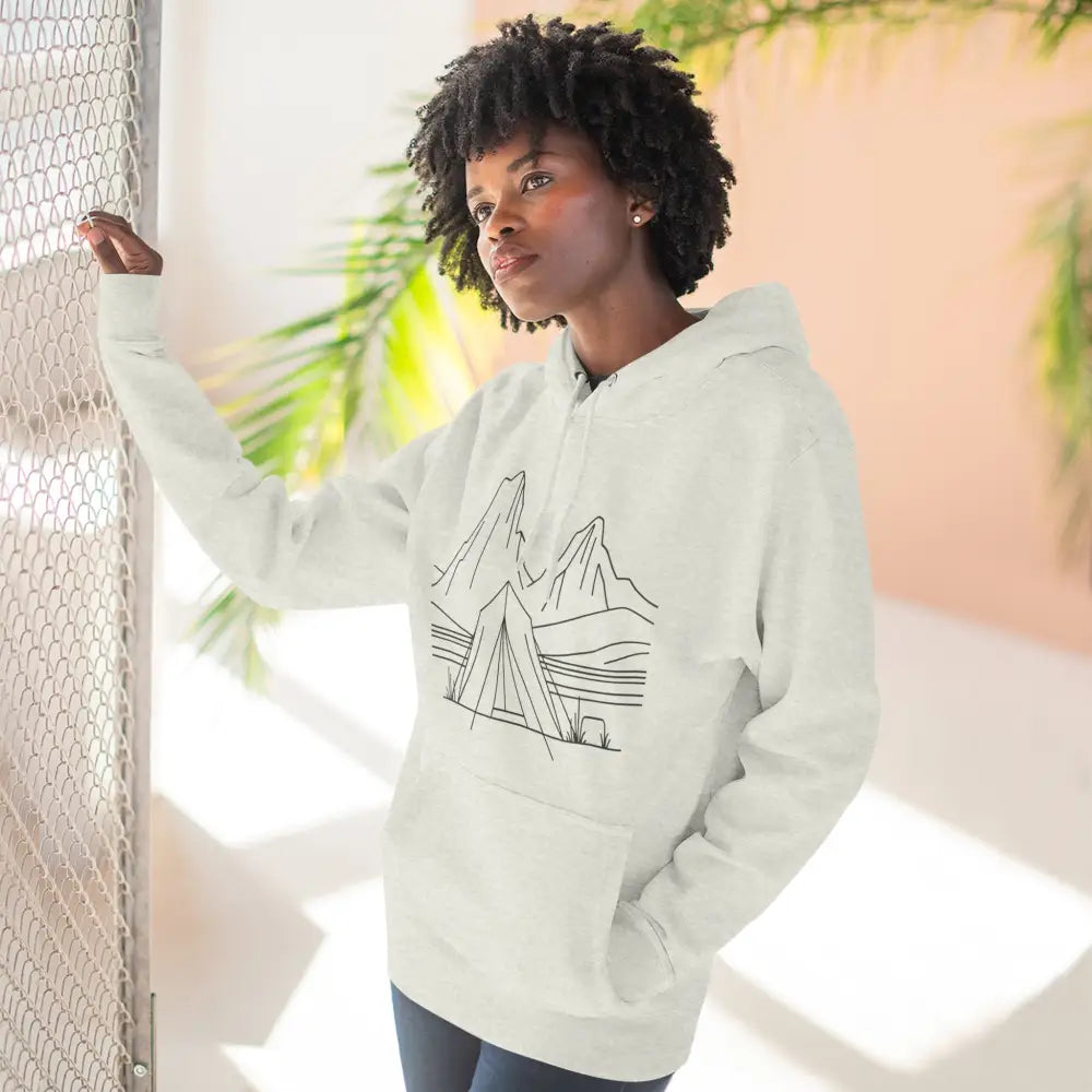 Woman wearing white graphic unisex hoodie with mountain and tent design, cozy fleece, spacious kangaroo pocket