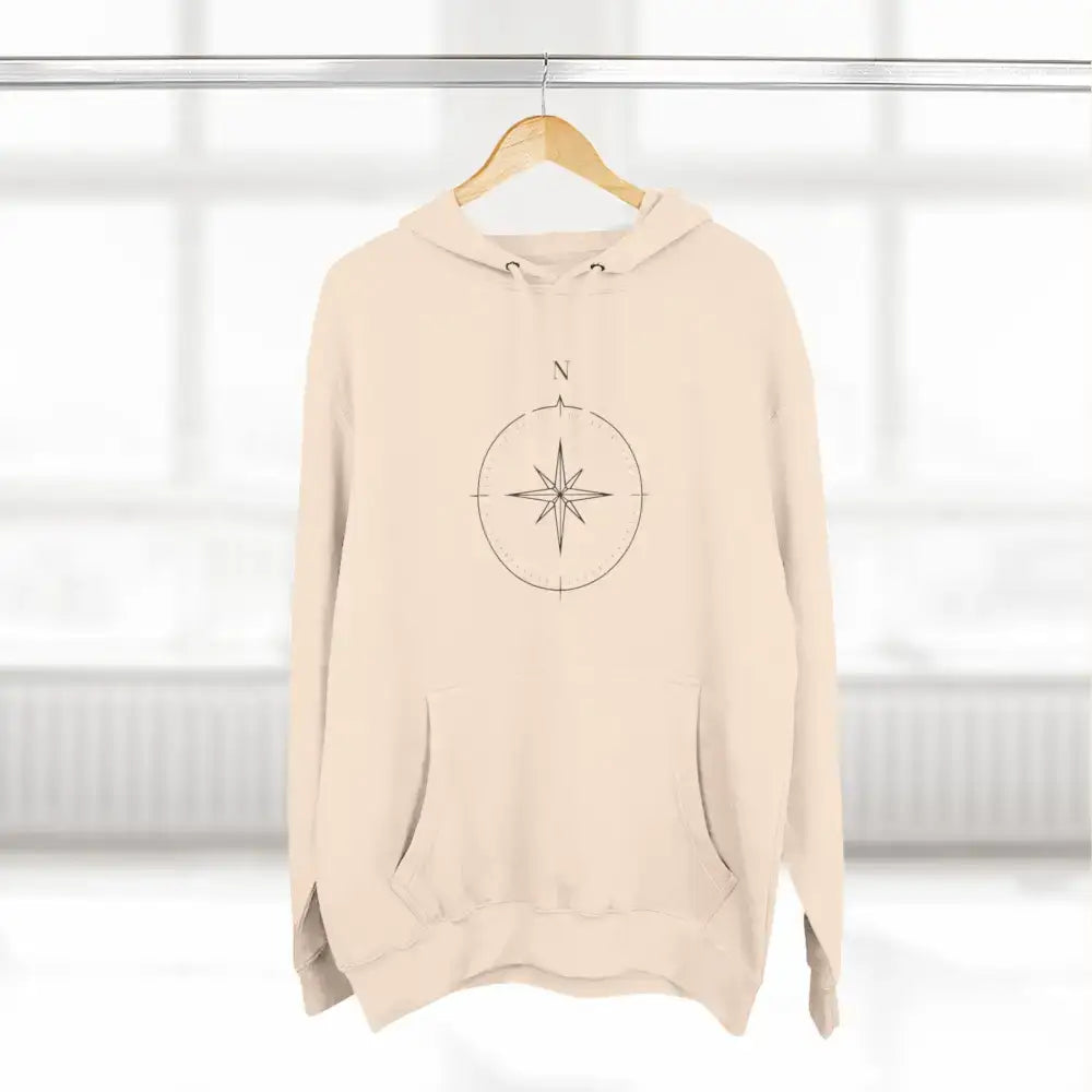 Cream-colored Cozy Compass Unisex Hoodie with adjustable hood and low heat care instructions