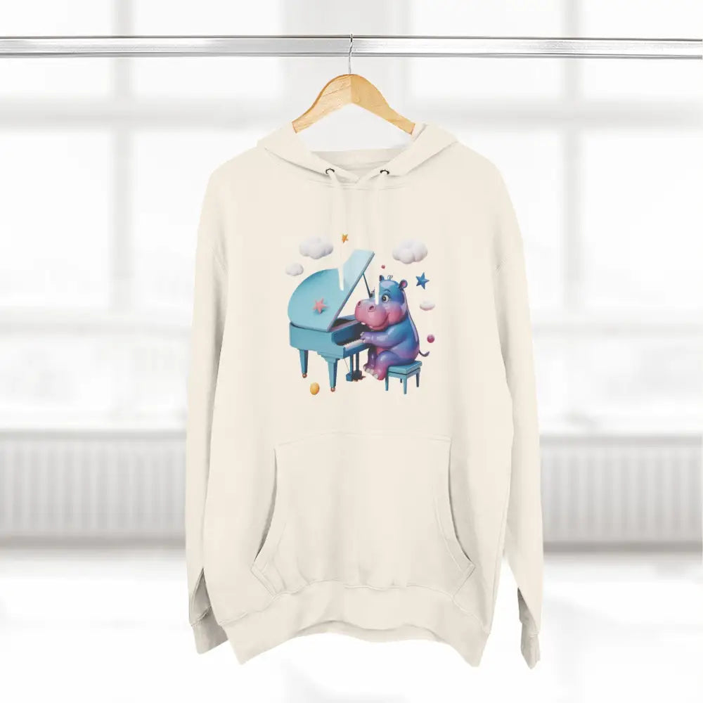 Cream-colored fleece hoodie with a cartoon hippo playing a light blue piano, perfect for kids and teens