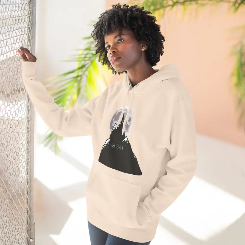 Woman wearing a cream-colored mountain scene fleece unisex hoodie ascend with moon graphic