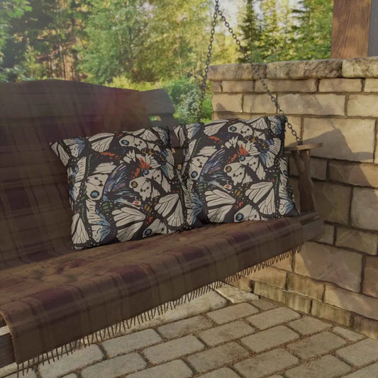 Outdoor lounge space with butterfly-patterned pillows and plaid blanket on wooden porch swing