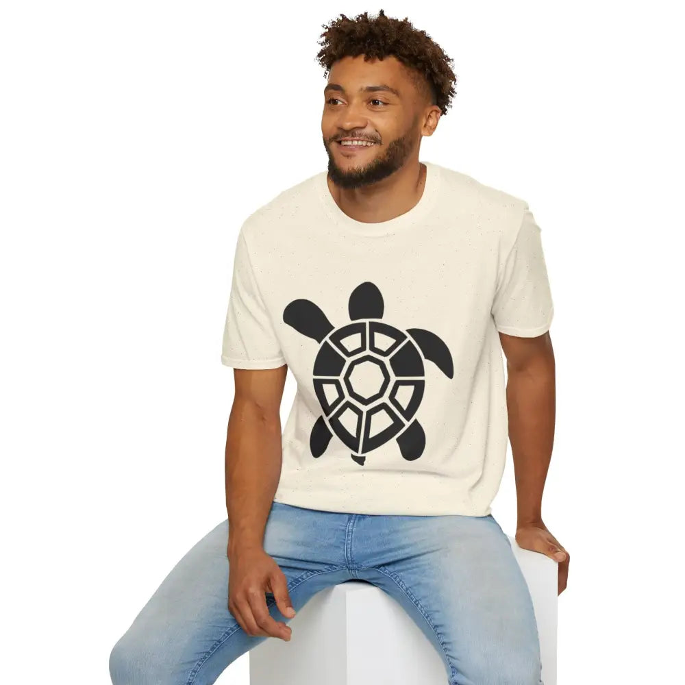 Man wearing cream Turtle Graphic Unisex Tee with black turtle design, casual beach outfit